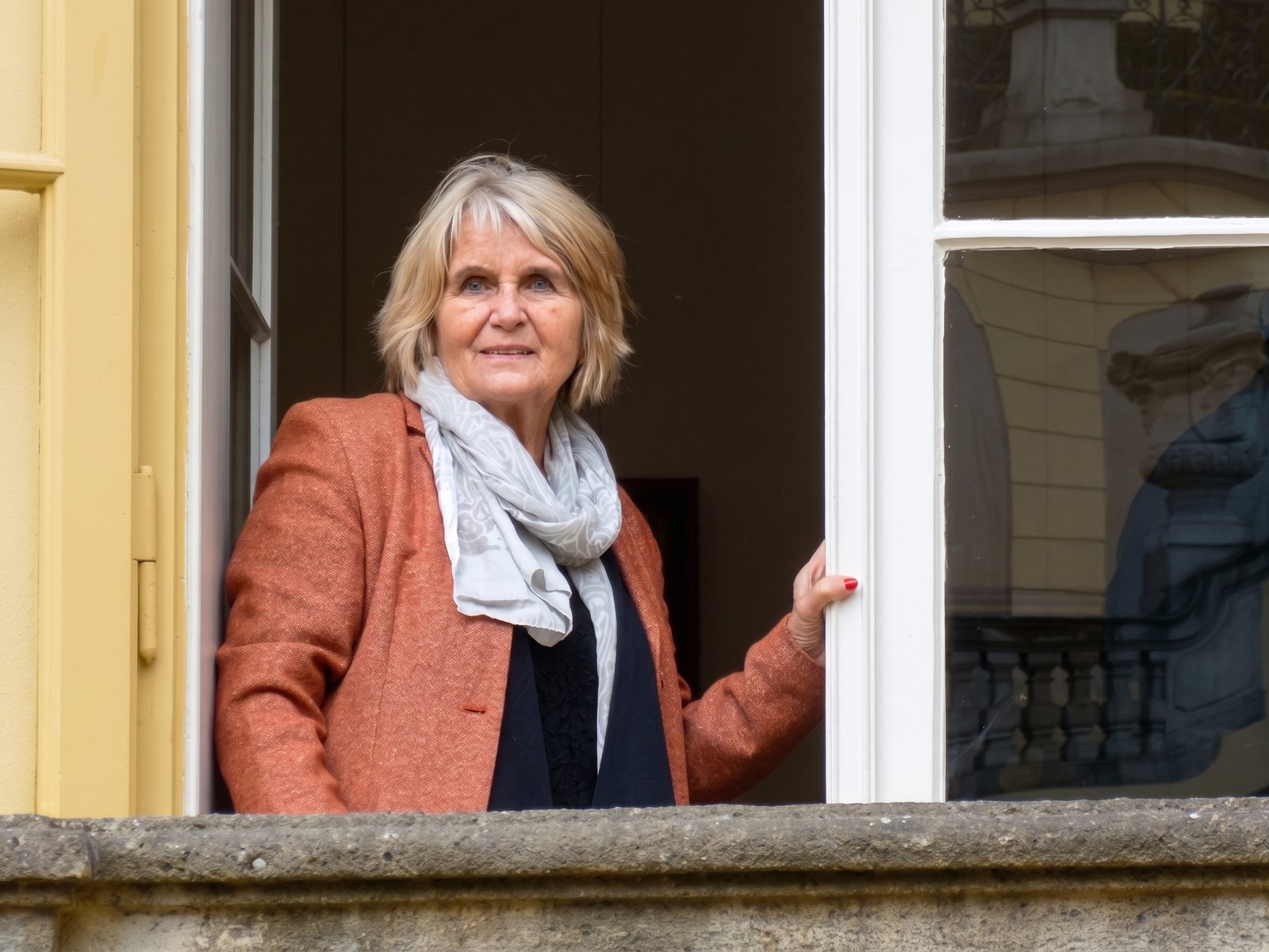 Frau am geöffneten Fenster eines historischen Gebäudes