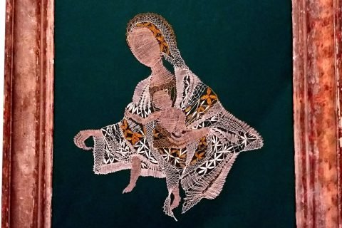 Gerahmtes Klöppelbild einer Madonna mit Kind auf grünem Grund