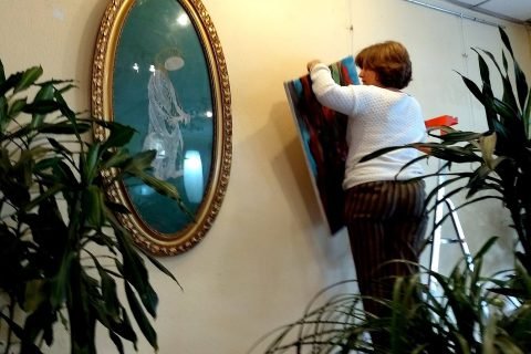 Eine Frau hängt ein Bild neben einem ovalen Rahmen auf
