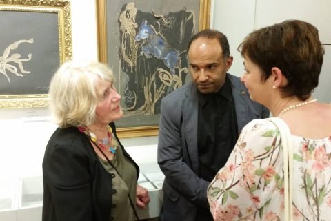 Besucher im Gespräch vor gerahmten Arbeiten