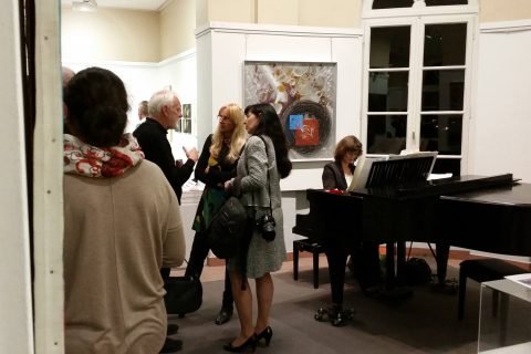 Blick in den Ausstellungsraum mit Besuchern und Flügel